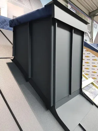 Komin obłożony grafitową blachą na rąbek z obróbką u podstawy na dachu