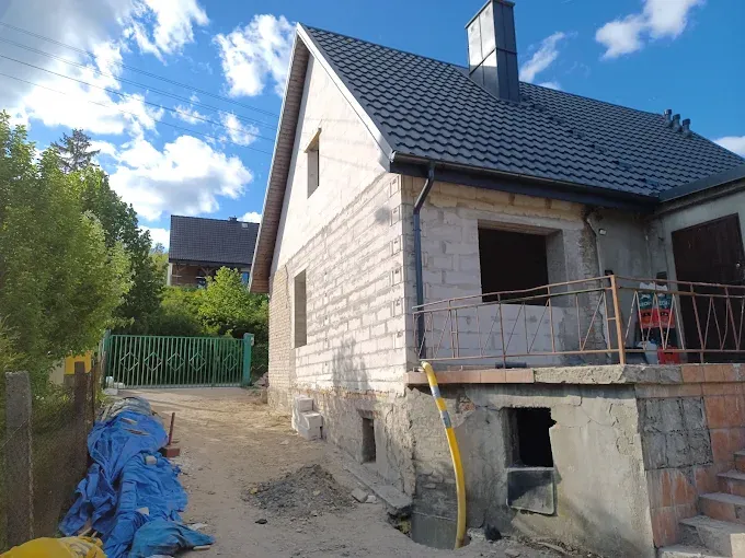 Dom w trakcie budowy z grafitowym dachem i obrobionym kominem