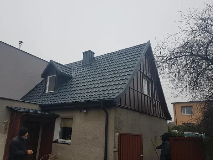 Dom z grafitowym pokryciem dachowym, lukarną i obitym szczytem